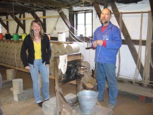 Mann in Museum erklärt das Seilerhandwerk, Frau steht lachend daneben