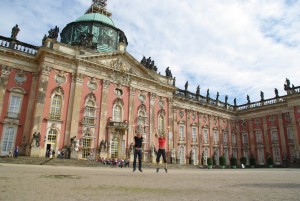 Mann und Frau springen hoch vor dem Neuen Palais in Potsdam