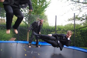 Drei Männer im Anzug springen auf einem Trampolin