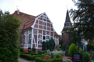 Kirche in Fachwerkbauweise, davor Gräber